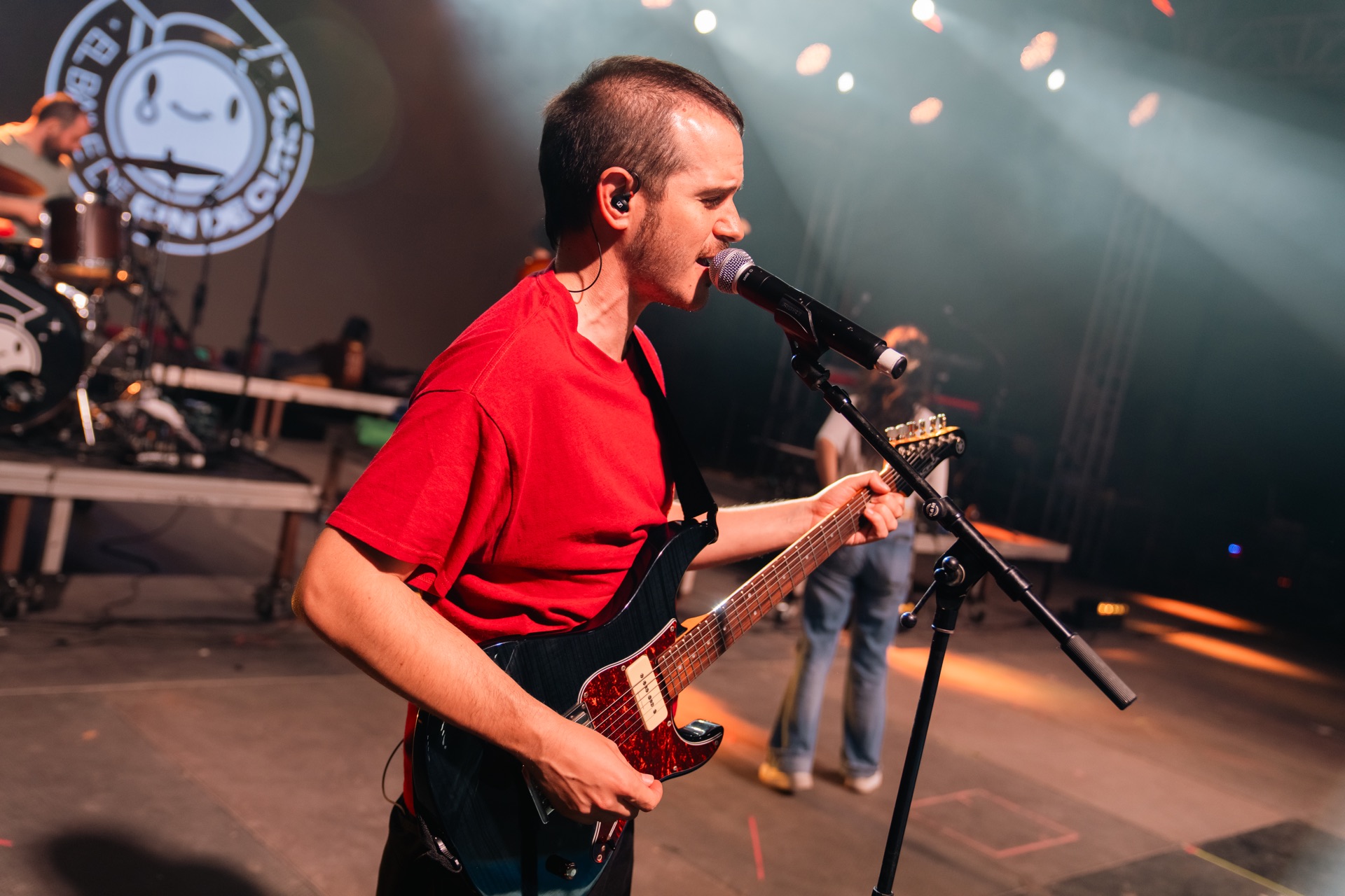 Guitarrista amb samarreta vermella cantant en directe